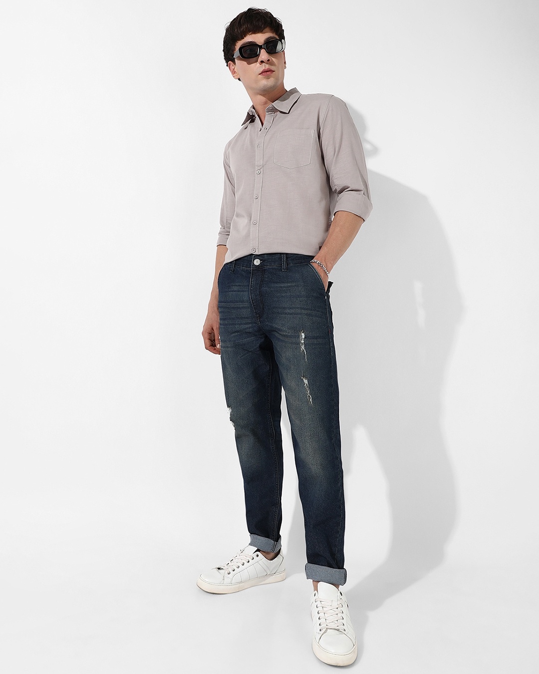 man styled a dark blue jean with grey shirt paired with sneakers