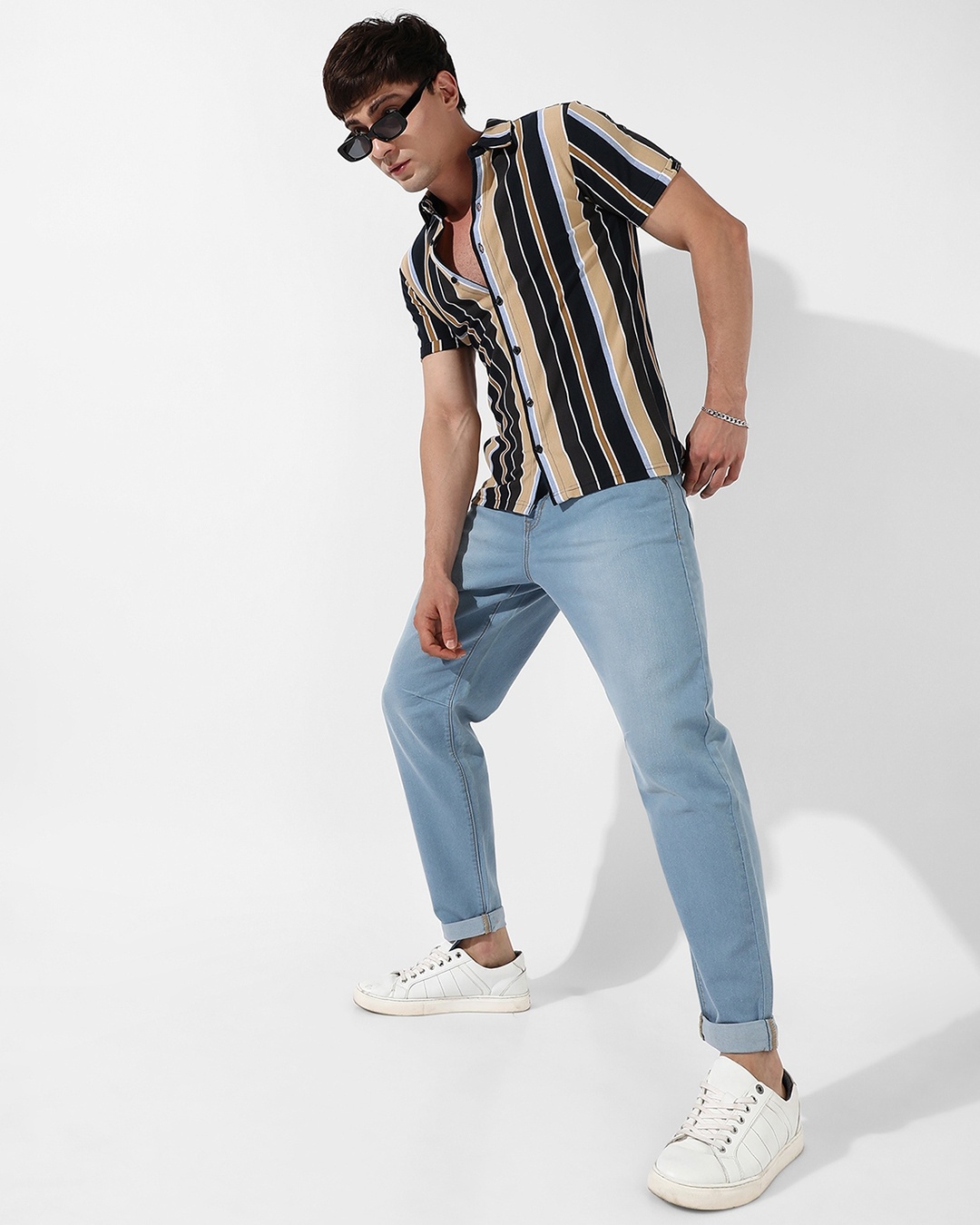 man giving a casual pose by wearing a light blue jean with striped shirt