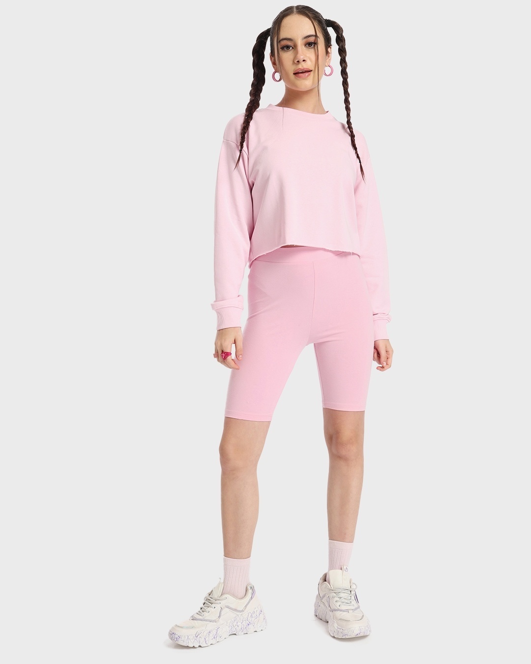 woman styled a pink sweatshirt with shorts and sneakers